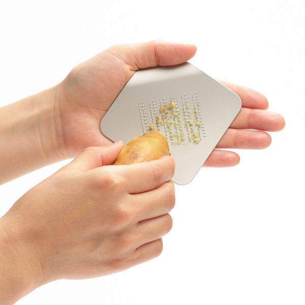 一枚の紙をめくったような形をしているこのおろし金は、角の捲れた部分が手のふちにちょうど良くフィットします。 おろし刃に当て、左右に動くことです